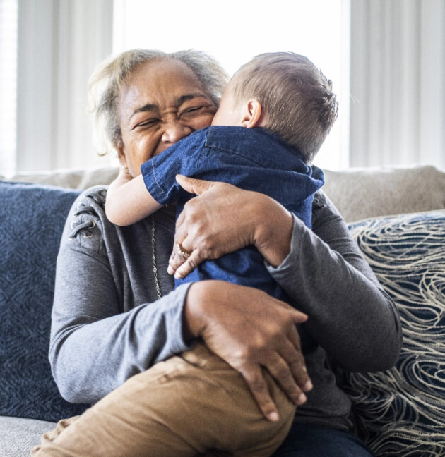 A grandmother joyfully embracing her young grandchild in a cozy home setting.