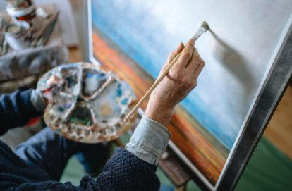 Senior creative art and craft professional painting an artwork in his home art studio during a peaceful morning.
